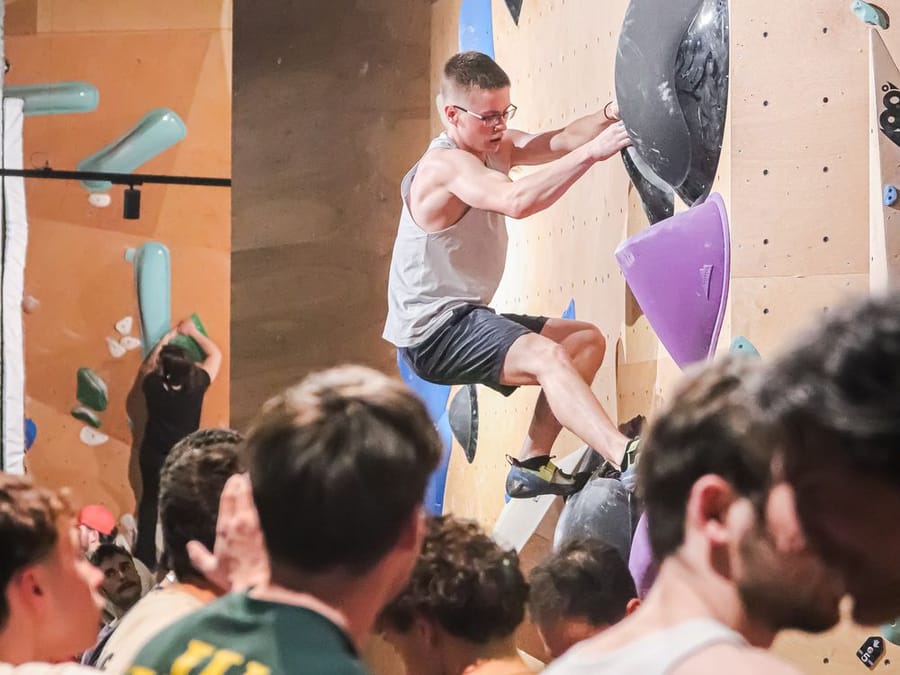 Un grimpeur dans un bloc, le public au pied du mur